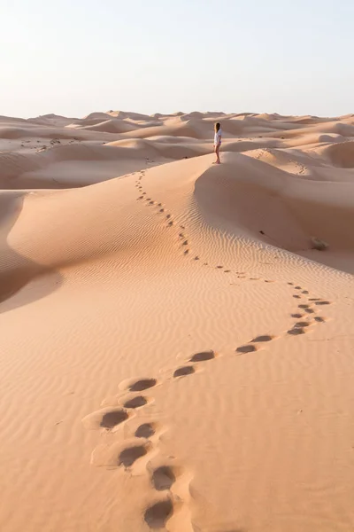 Blonde female Caucasian traveler leaving footprints in sand dunes when walking in dessert in Oman — Stock Photo, Image