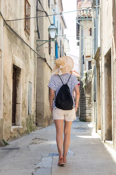 Vista trasera de la hermosa rubia joven viajera con sombrero de sol de paja turismo y disfrutar de vacaciones de verano en una antigua ciudad costera tradicional a costa del Adriático, Croacia — Foto de Stock