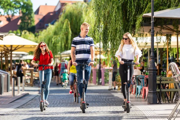 Trendy divatos baráti társaság lovaglás állami bérleti elektromos robogók városi környezetben. Új környezetbarát, modern tömegközlekedés Ljubljanában, Szlovéniában — Stock Fotó