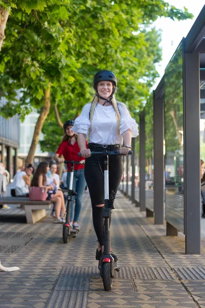 Trendi divatos tizenéves lányok lovaglás állami bérleti elektromos robogók városi környezetben. Új környezetbarát, modern tömegközlekedés Ljubljanában, Szlovéniában — Stock Fotó