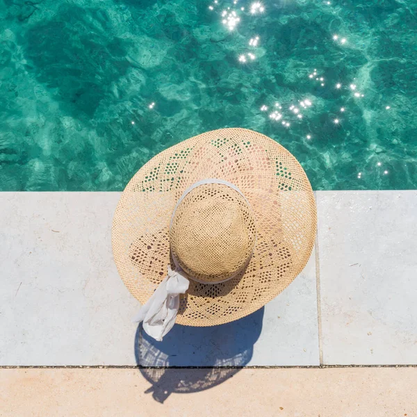 Vrouw dragen grote zomer zon hoed ontspannen op pier door helder turquoise zee. — Stockfoto