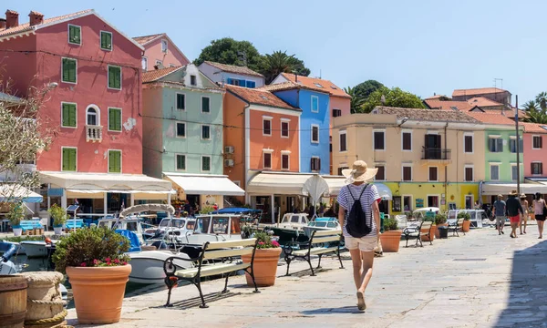 Visão traseira da bela loira jovem viajante vestindo chapéu de sol palha passear e desfrutar de férias de verão em uma antiga cidade costeira tradicional de Veli Losinj, Adriático custo, Croácia — Fotografia de Stock