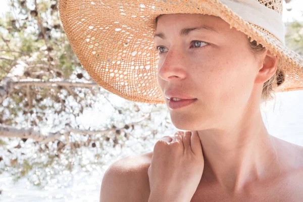 Primer plano retrato de no maquillaje natural hermosa sensual mujer con sombrero de sol de paja en la playa a la sombra de un pino —  Fotos de Stock