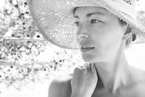 Nahaufnahme Porträt ohne Make-up natürliche schöne sinnliche Frau trägt Strohsonnenhut am Strand im Schatten einer Kiefer in schwarz-weiß. — Stockfoto