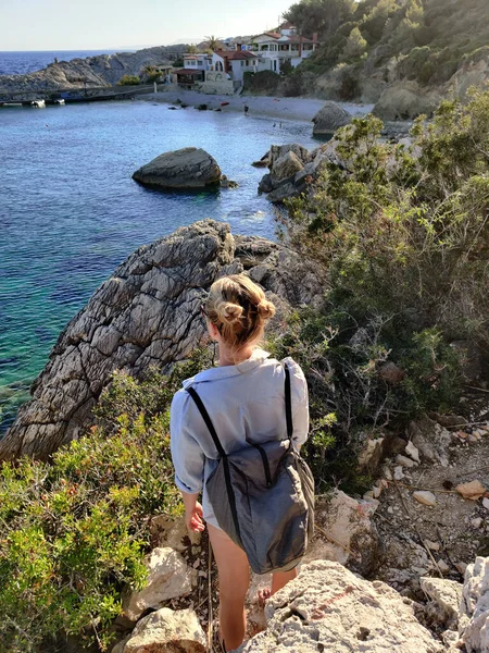 Joven turista activo con una pequeña mochila caminando por el sendero costero entre pinos disfrutando de una hermosa vista costera de la playa de Velo Zarace en la isla de Hvar, Croacia. Concepto de viaje y aventura — Foto de Stock