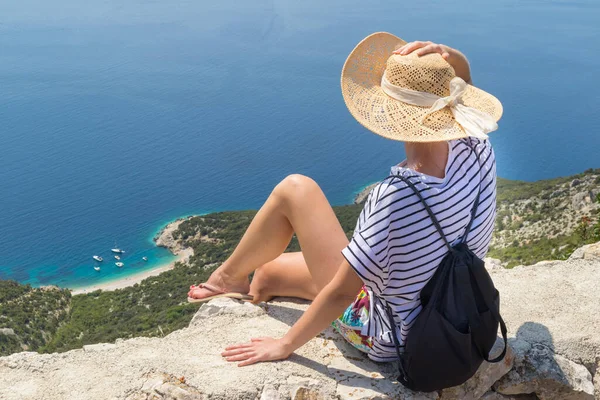 Mulher esportiva ativa em férias de verão sentado na antiga parede de pedra na aldeia de Lubenice, vestindo chapéu de palha e mochila de praia desfrutando de bela vista costeira da ilha de Cres, Croácia — Fotografia de Stock