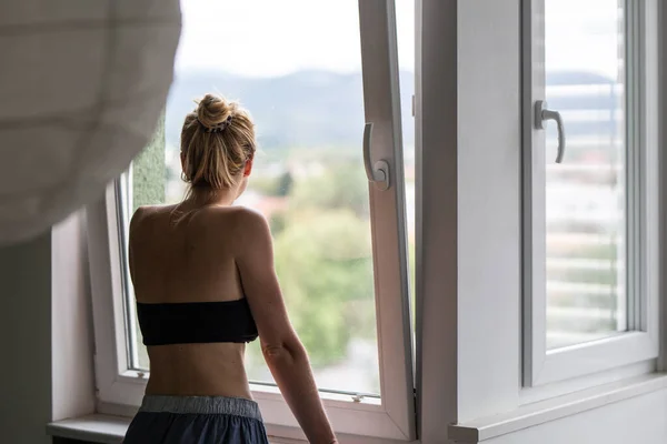 Home quarantine and social distancing during covid pandemic. Silhouette of lonley caucasian woman standing by window, anxiously looking out. Coronavirus infection, pandemics, disease outbreaks — Stock Photo, Image