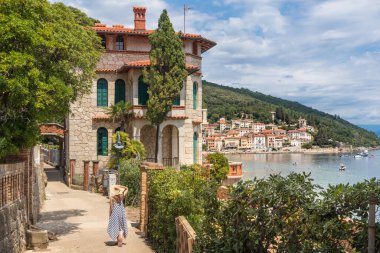 Adriyatik kıyısı boyunca yürüyen kadın turist, Hırvatistan 'ın Istria kentindeki Moscenicka Draga kentinde tatil yaparken dinleniyor.