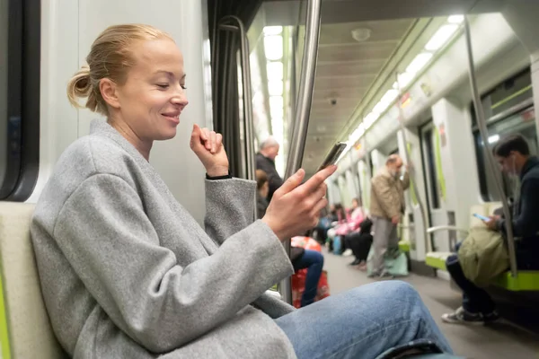 Porträtt av härlig flicka skriva meddelande på mobiltelefon i nästan tomma offentliga tunnelbanan tåg. Vistelse i hemmet och socialt avståndstagande rekomenderat på grund av koronaviruspandemi utbrott — Stockfoto