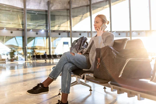 공항 출입문에서 비행기를 기다리는 동안 핸드폰을 사용하는 음탕 한 젊은 여자. 코로나 바이러스 유행병으로 인한 빈 공항 터미널 — 스톡 사진