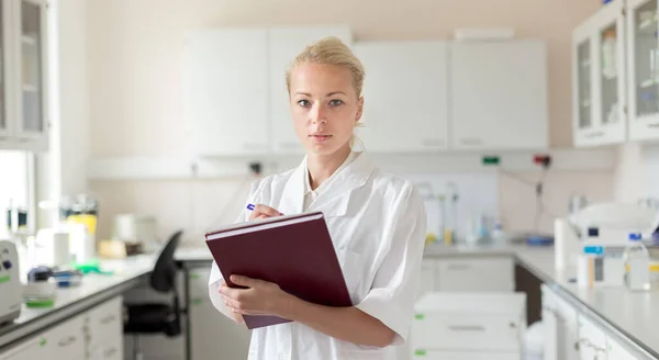 Portrait of young, confident female health care professional taking notes during inventory in scientific laboratory or medical doctors office — Stock Photo, Image