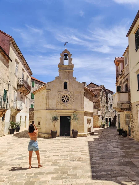 Female tourist taking photo of mall church on square of small urban village of Stari grad on Hvar island in Croatia, Adriatic Sea, Europe — Stock Photo, Image