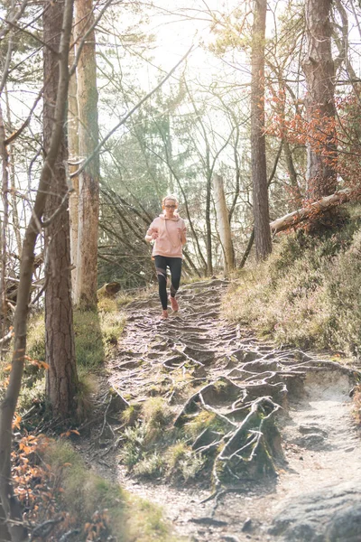 Mujer deportiva activa escuchando la música mientras corre en otoño bosque de otoño. Corredor femenino entrenando al aire libre. Estilo de vida saludable imagen de la joven mujer caucásica corriendo fuera —  Fotos de Stock