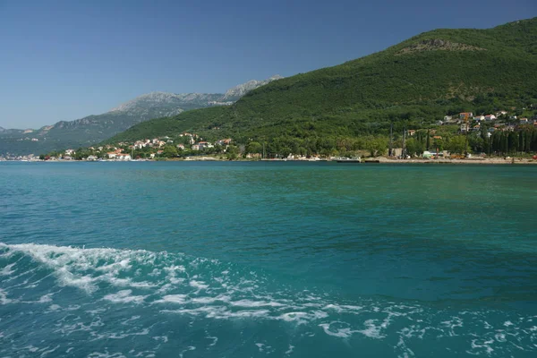 the sea, the houses and the forested hills of Montenegro on a summer day. View from the boat