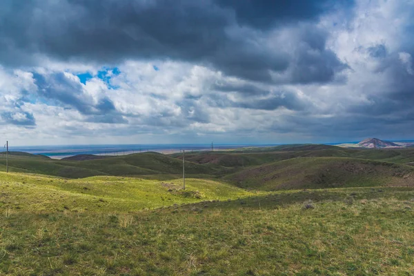Kırmızımsı tepeler, bulutlu bir günde ilk bahar çimen ile kaplı. Çevresi Arkharly Pass, Kazakistan