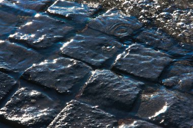 Gri mahsul doğal kentsel kaldırım taşlarının dokusu suyun altında yakındır.