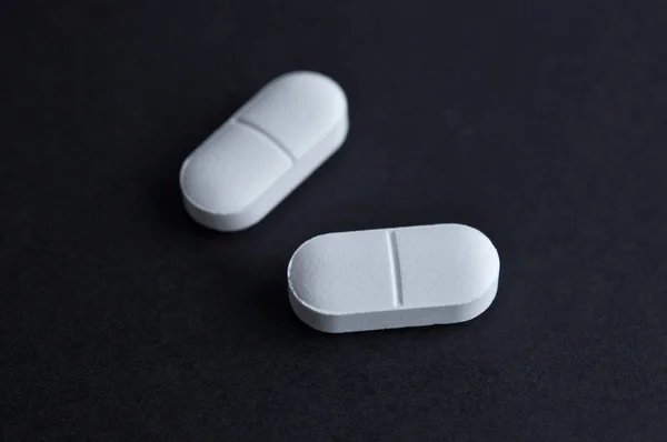 Zwei Weiße Pillen Auf Schwarzem Hintergrund Medikamentenkonzept — Stockfoto