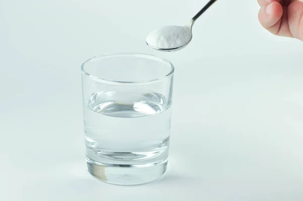 Μαγειρική σόδα, το κουτάλι και το ποτήρι του νερού. — Φωτογραφία Αρχείου