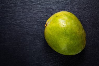 Üstten görünüm yeşil mango siyah arduvaz taş tahta üzerinde