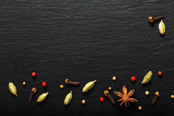 Food presentation background organic various exotic spieces on black slate board with copy space