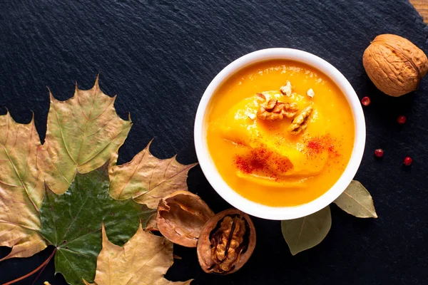 Autumn winter food concept Pumpkin or butternut soup on black slate stone plate