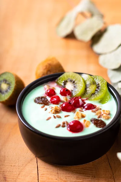 Healthy food colorful Yogurt Breakfast Bowl  with kiwi, flax seeds, Granola, and red currants in black ceramic bowl with copy space