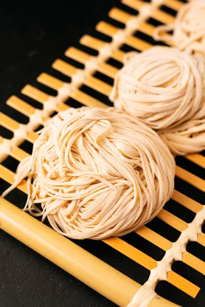 Asiatico cibo concetto fatto in casa uncook orientale uovo tagliatelle su bambo — Foto Stock