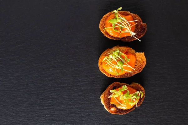 Conceito de comida saudável hummus abóbora vegan com linho microgreen canapés pão em placa de ardósia de pedra preta com espaço de cópia — Fotografia de Stock