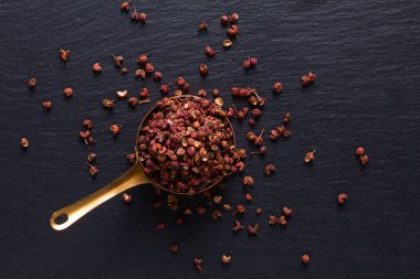 Gıda baharatları konsepti organik Sichuan 'ın üst görüntüsü, bakır bardaktaki Szechuan biberi siyah taş üzerinde fotokopi alanı ile