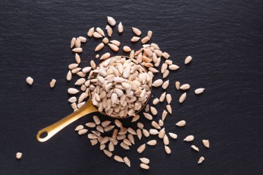 Yiyecek baharatları konsepti. Bakır bardaktaki organik ayçiçeği tohumunun fotokopi alanı olan siyah kayanın üzerindeki görüntüsü.