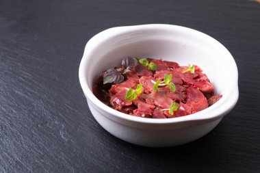 Fransız Gıda Gıdaları de Poulet, beyaz seramik bardakta siyah tahta üzerinde fotokopi alanı olan tavuk Gizzard 'a el koyuyor.