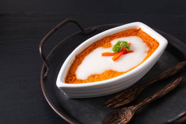 Asya gıda konsepti Tayland körili balığı buğulanmış kırmızı köri kremalı Hor mok beyaz seramik tekne şeklinde kırsal demir tepside siyah arka planda. 