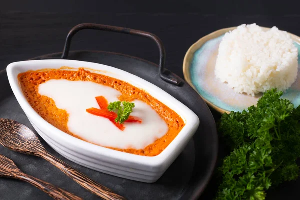 Asya gıda konsepti Tayland körili balığı buğulanmış kırmızı köri kremalı Hor mok beyaz seramik tekne şeklinde kırsal demir tepside siyah arka planda. 