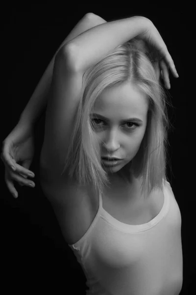 Black-and-white portrait of blonde in white T-shirt on a black background.