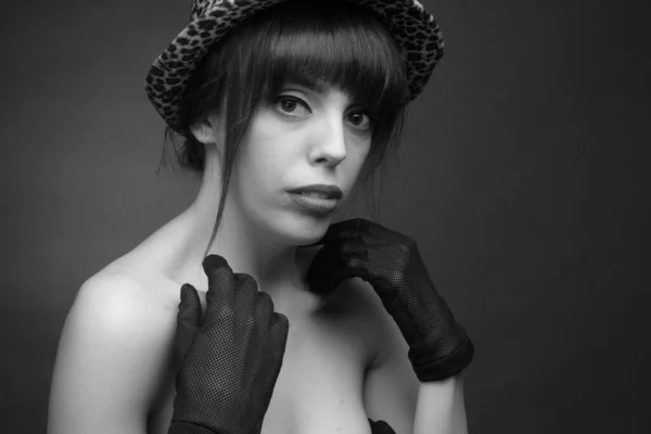 black and white portrait of brunette with long hair, off shoulder. In a spotted hat and black gloves