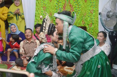 TARAKAN - İNDONEZYA, 16 Mart 2019: damat bir evlilik töreninde gelinin alnını öpüyor.