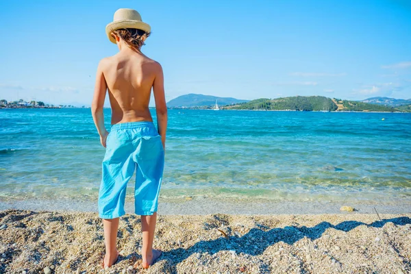 Vista trasera del niño caminando en la hermosa playa junto al agua —  Fotos de Stock