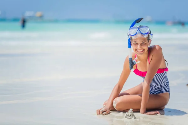 Girl in swimsuit and scuba mask sitting and having fun on tropical beach — Stock Photo, Image