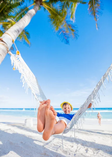 Niño feliz sentado en hamaca en la playa tropical — Foto de Stock