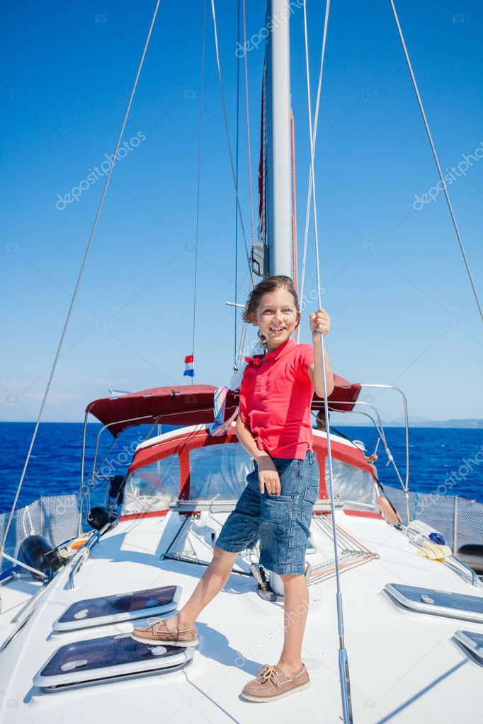 Little boy on board of sailing yacht on summer cruise. Travel adventure, yachting with child on family vacation.