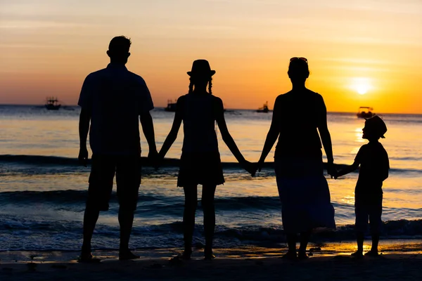 Silhouette einer glücklichen Familie, die am Strand bei Sonnenuntergang Spaß hat. — Stockfoto