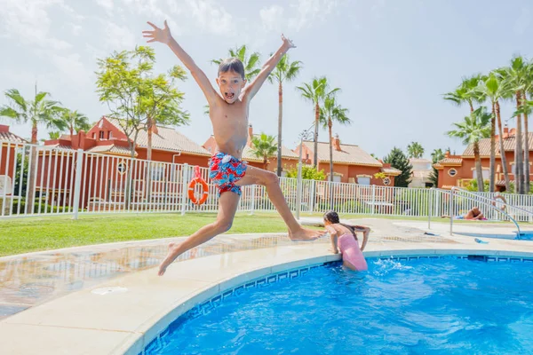 Rapaz feliz saltando na piscina — Fotografia de Stock