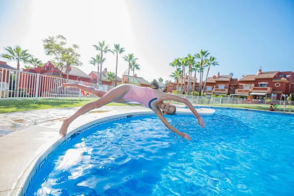 Menina feliz pulando na piscina — Fotografia de Stock