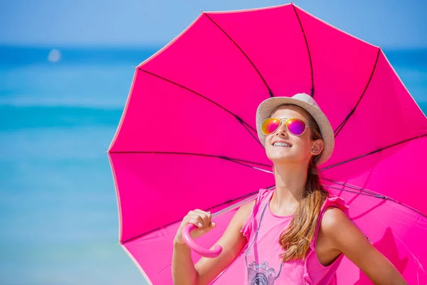 Flicka med en rosa paraply på sandstranden — Stockfoto