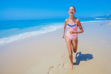 Girl in swimsuit runing and having fun on tropical beach clipart