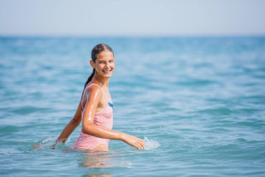 Girl in swimsuit having fun on tropical beach clipart
