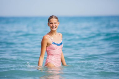 Girl in swimsuit having fun on tropical beach clipart