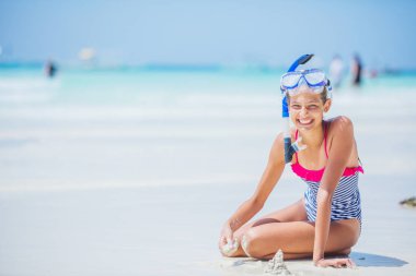 Oturma ve tropik sahilde eğleniyor mayo ve tüplü maske kız