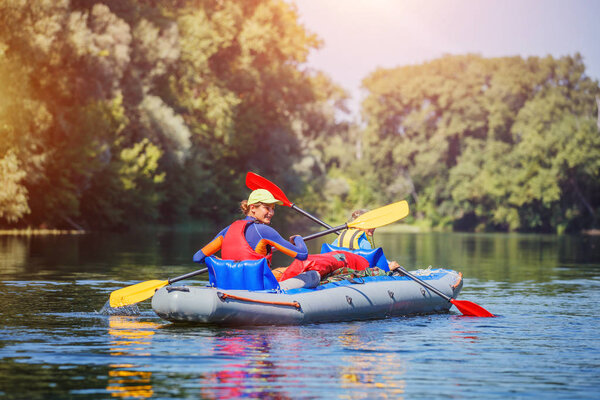 Счастливая девушка катается на байдарке по реке в солнечный день во время летних каникул