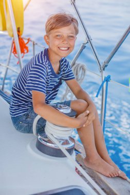 Cute boy on board of sailing yacht on summer cruise. Travel adventure, yachting with child on family vacation. Kid clothing in sailor style, nautical fashion. clipart